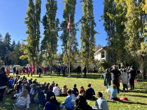Outdoor ceremony in Colwood with a crowd gathered around a flagpole, featuring school children and officials.