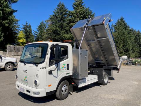 White zero-emission Colwood fleet vehicle with a raised bed, showing its dumping mechanism.