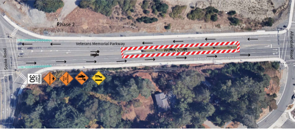 Aerial view of Veterans Memorial Parkway showing work zones and traffic signs for road construction phases, with visible traffic flow directions.